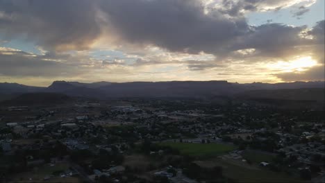 Eine-Langsame-Drohnenaufnahme-über-Einem-Kleinen-Dorf-Im-Westen-Mit-Einem-Majestätischen-Sonnenaufgang-Und-Wunderschönen-Wolken,-Die-Die-Berge-Im-Hintergrund-Erhellen