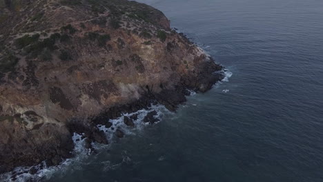 AERIAL:-flight-over-Malibu,-California-view-of-beach-Shore-Line-Pacific-ocean-at-sunset-with-mountain-cliff