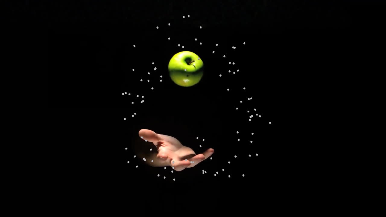mano alcanzando hacia la manzana verde flotante con animación de partículas en fondo negro