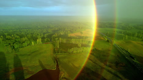 a smooth panoramic shot of a grassy landscape that has a forest and a lake with a rainbow reflection