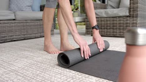 a person is rolling up yoga mat on a patterned rug outdoors