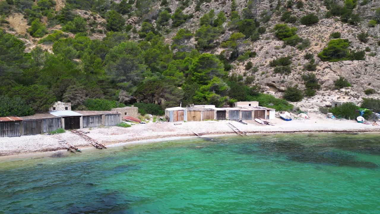 Cala Llentrisca, a secluded beach in Ibiza, highlighting the pristine turquoise waters and surrounding verdant landscape. Brilliant aerial view flight drone shot from above