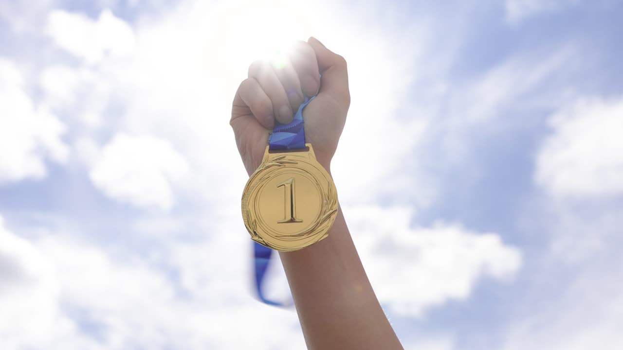 Hand holding award medal in outdoor setting with sky background. Symbol of success, achievement, victory, and recognition. Perfect for motivation, goals, and winning concepts