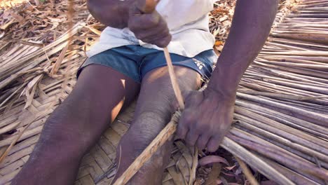 a native of moheli or mwali, comoros making a wandza roof element on the ground - close up
