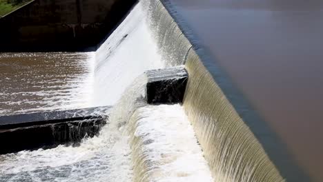 close-up of a small dam's spillway with water surging over, capturing dynamic flow. ideal for nature, hydrology, and environmental projects