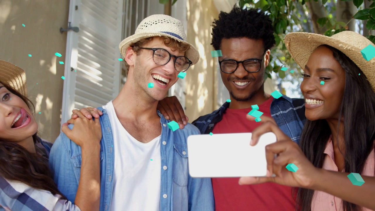Amici che si appoggiano, donna che tiene il telefono in fuori, scattando un selfie sociale, coriandoli color verde acqua che fluttuano su di loro.
