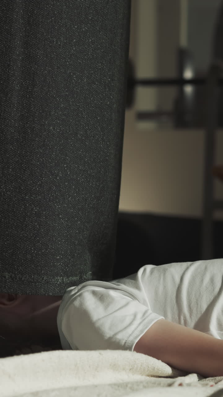 스포츠 센터에서 누워있는 아이 위에 돌을 던지는 주머니. 직물 케이싱의 가장자리는 무술 체육관에서 작은 소녀의 얼굴을 만니다. 느린 동작. 피곤한 아이는 바닥에 휴식을 취합니다.