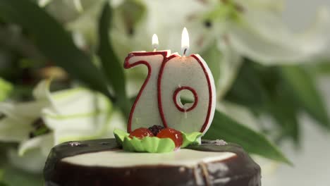 white lily bouquet and chocolate cake with candle number 70