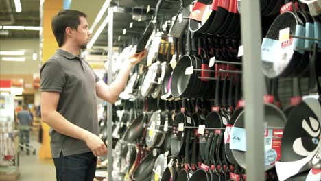 hombre comprando ollas y sartenes en una tienda de comestibles