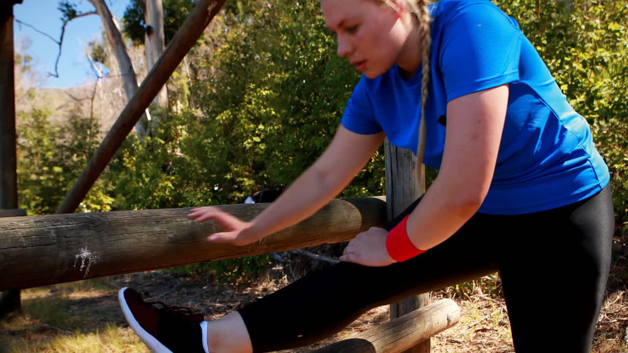Mulher determinada se exercitando durante um percurso de obstáculos.