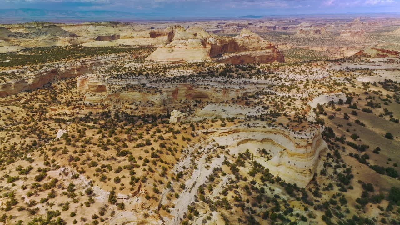 Rocky landscape of endless desert with little bushes of greenery. Amazing canyons of Utah, USA at the backdrop of blue sky.