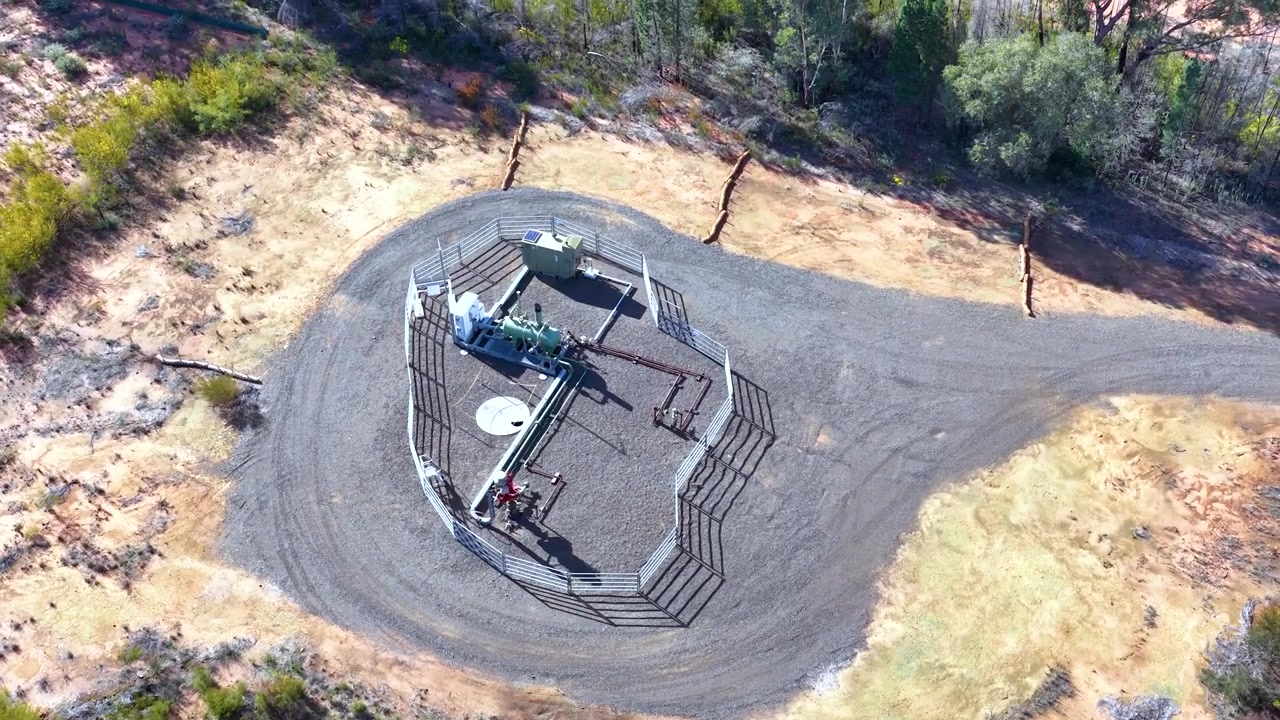 Aerial view of an industrial gas well site surrounded by bushland in Australia.