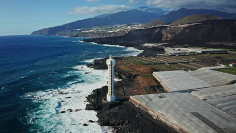 drone aéreo disparado sobre la costa volcánica negra en la palma, islas canarias, españa. alta vista del faro, olas del océano aplastando las rocas.