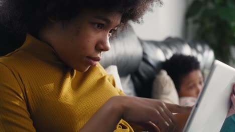 Teenage-girl-browsing-digital-tablet-in-the-living-room