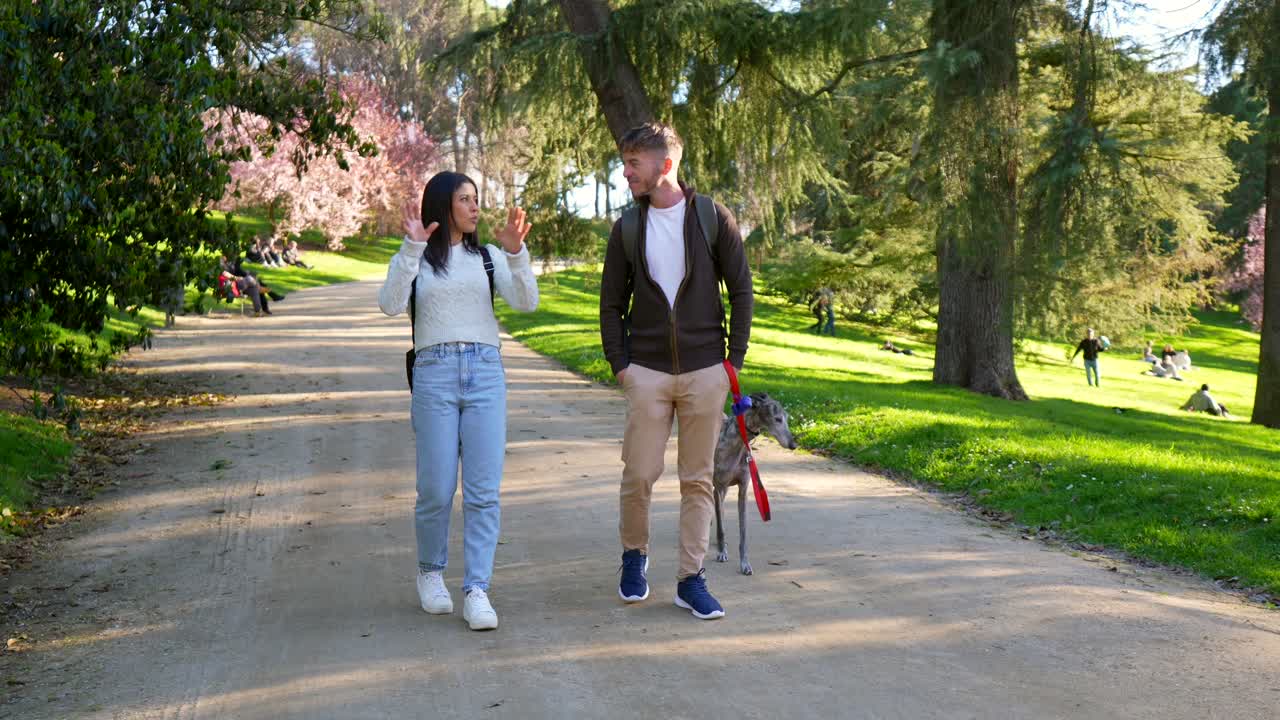 Pareja paseando y conversando con su perro en un parque soleado