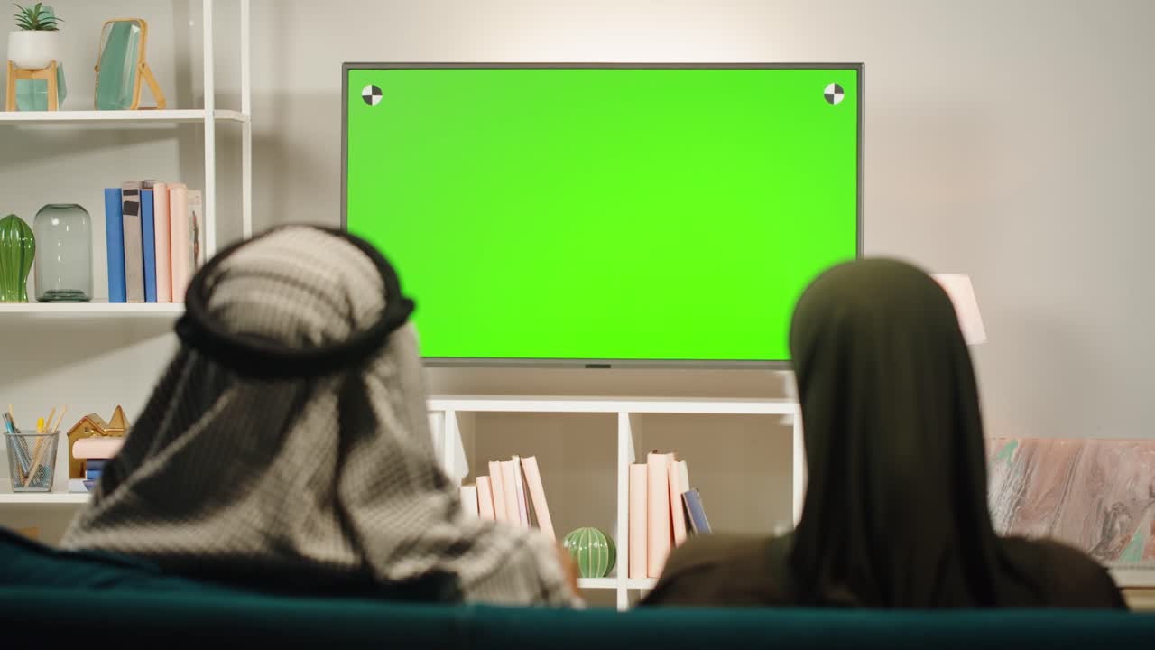 Middle Eastern couple watching a green screen TV at home