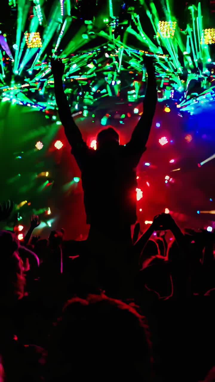 Sagoma di una persona a un concerto, braccia alzate, con luci sceniche vivaci.