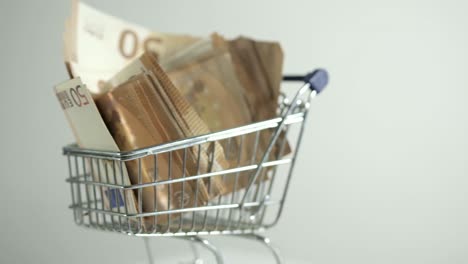 carrito de compras girando en su propio centro billetes de 50 euros girando dinero estudio disparado