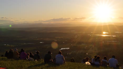 group of people watching sunset over vast landscape