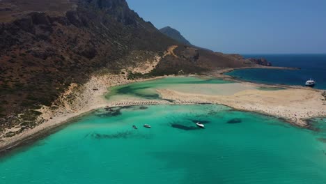 Antena-Descendiendo-Sobre-La-Playa-De-Balos-Y-La-Laguna-Con-Agua-Turquesa,-Montañas-Y-Acantilados-En-Creta,-Grecia