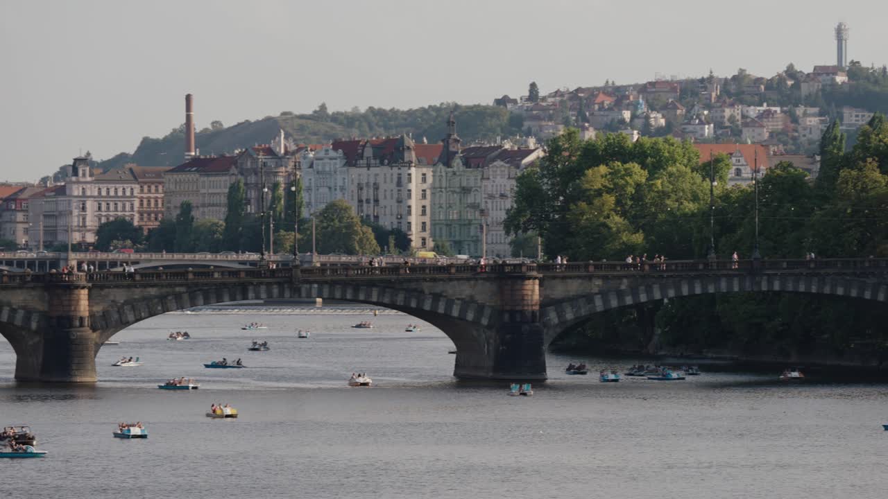 Closer view of the Legions Bridge over the Vltava River with paddle boats and historic buildings in Prague