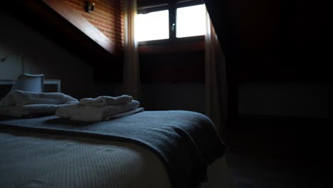 cozy attic bedroom with white towels and gray blanket