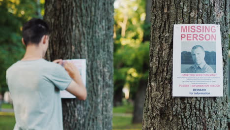 a young man puts up ads for a missing person in the park