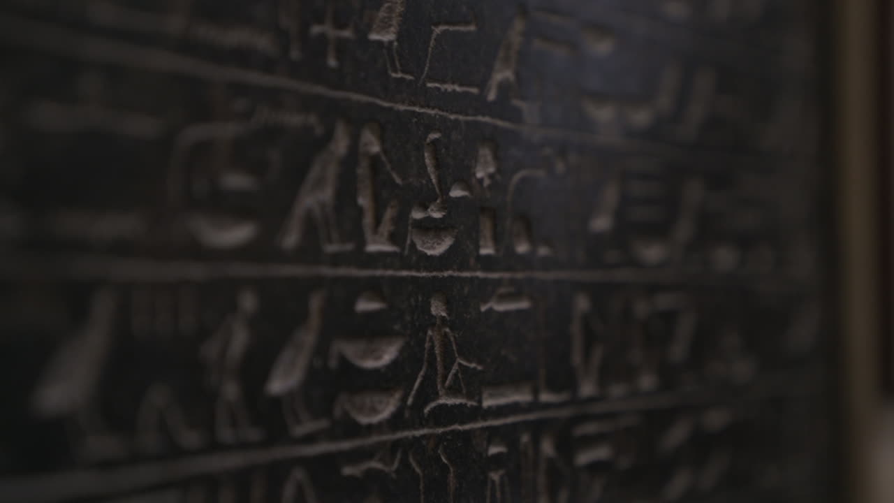 Macro shot moving down dark wall covered in ancient Egyptian hieroglyphics