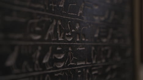 macro shot moving down dark wall covered in ancient egyptian hieroglyphics