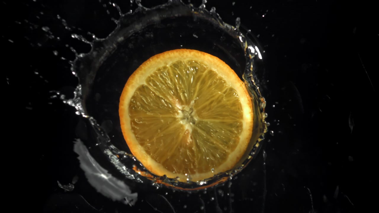 Fetta d'arancia che si tuffa nell'acqua al rallentatore
