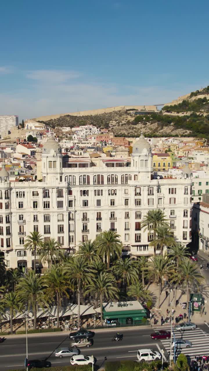Lodret drone-stockoptagelse fra luften, der fanger Casa Carbonell i Alicante og den palmekantede promenade langs den spanske kystlinje