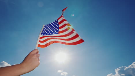 american flag against the backdrop of a serene blue sky and sun 1