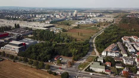 suburb district of vienna city with companies and housing area at cloudy day. aerial orbit wide shot. rural fields and austrian neighborhood in summer.