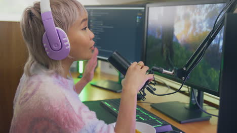 Mujer-Comiendo-Bocadillos-Mientras-Juega-En-Casa-Sentada-En-El-Escritorio-Usando-Auriculares-Para-Transmitir-En-Vivo