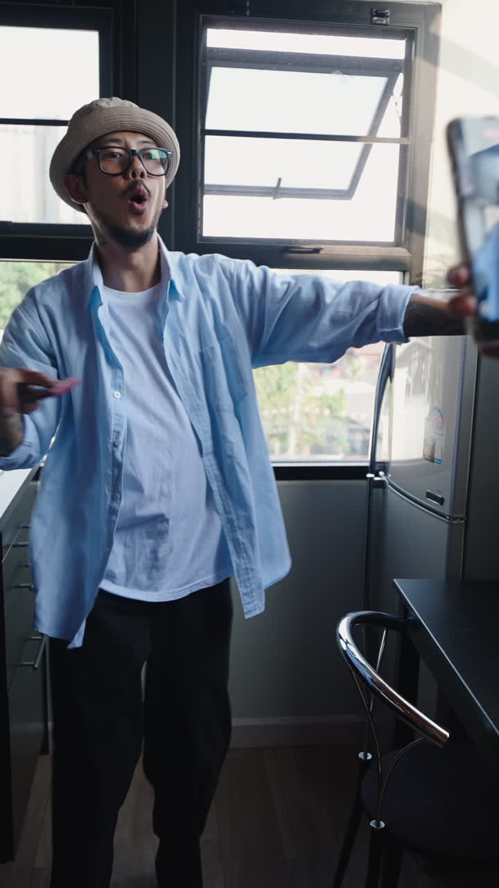 Homem dançando em local fechado enquanto é filmado com um celular