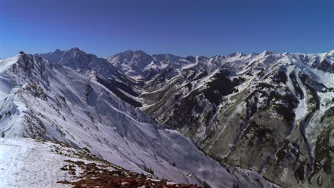 winter maroon bells capital peak wilderness jagged peaks aspen highlands ski resort bowl backcountry high alpine steep terrain colorado landscape blue sky deep snow sunny panorama pan left
