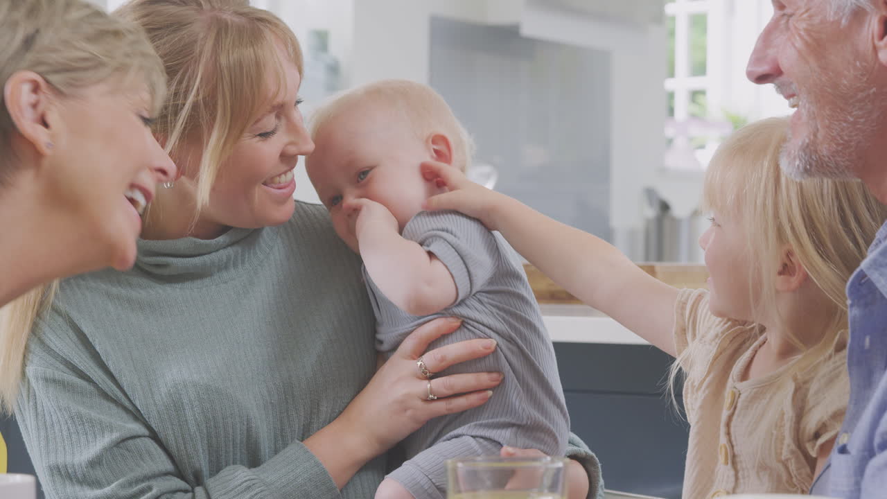 집 에서 주방 테이블 을 둘러싸고 앉아 있는 성인 딸 과 손자 들 과 함께 하는 할아버지 와 할머니