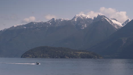 Speed-boat-cruising-ocean-with-Snow-peaks-in-background