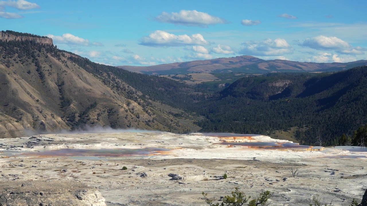 Mammoth Hot Springsin terassit, geoterminen kalkkikivimuodostelma, luonnonkaunis maisema Yellowstonen kansallispuistossa Wyomingissa. Syksyinen iltapäivä, aurinkoinen sininen taivas pilvineen. Pohjoinen sisäänkäynti, Madison Junction, Roosevelt.