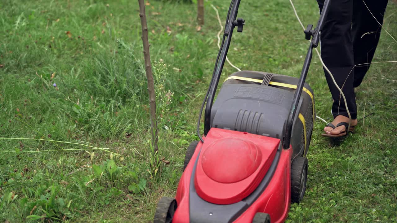 lawn mower at work on a green meadow at summertime