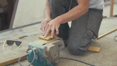 sanding down square capping wood piece using belt sander