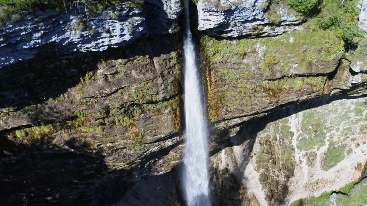 vista aérea de la cascada pericnik que fluye verticalmente desde una altura, entre el arroyo en empinadas montañas rocosas