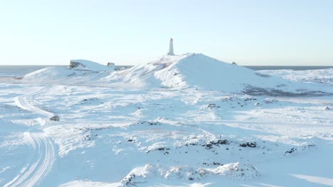 white winter landscape at reykjanes lighthouse on hill and car driving on road