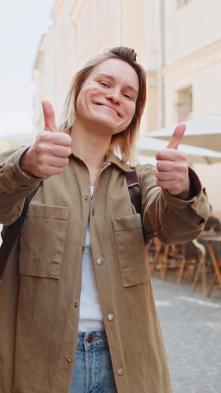 Mujer feliz mostrando pulgares hacia arriba como señal positiva algo bueno retroalimentación positiva en la calle de la ciudad