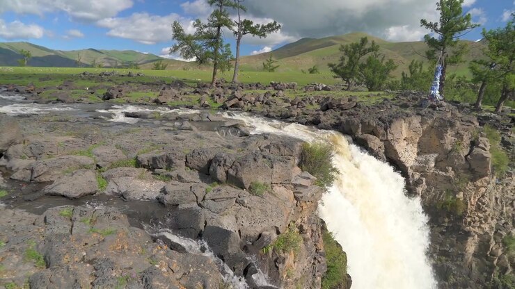 Cascata panoramica che scorre su terreno roccioso in un paesaggio mongolo