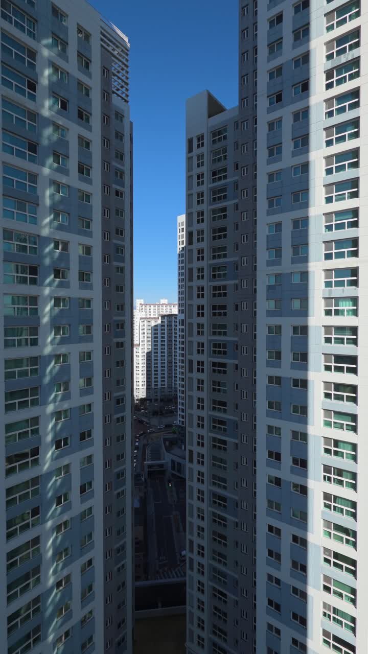 Plano vertical com drone panorâmico à direita para revelar um aglomerado denso de arranha-céus residenciais modernos e complexos de apartamentos no centro de Daegu, Coreia do Sul