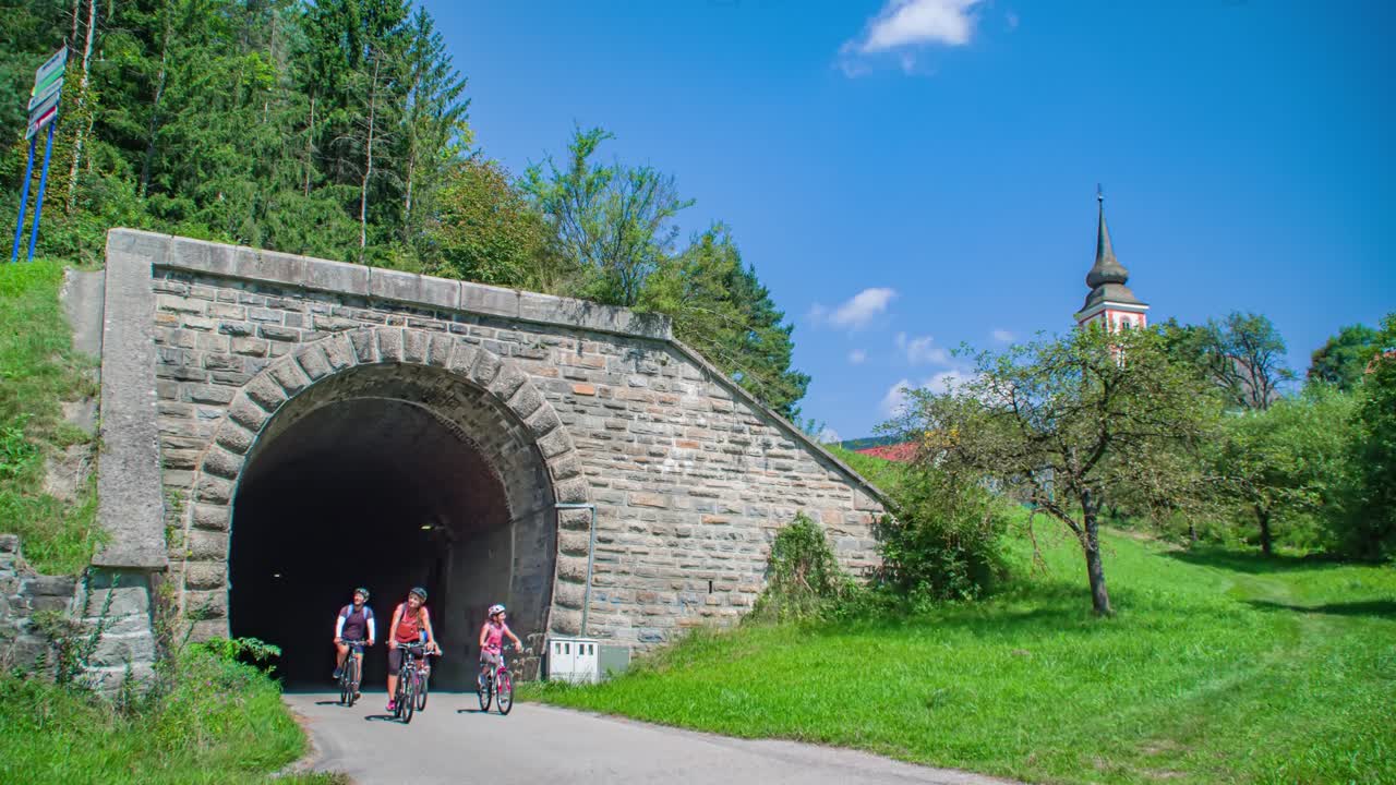 Lifestyle family of four cycling out tunnel path in Slovenia, dolly side