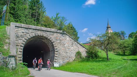 lifestyle family of four cycling out tunnel path in slovenia, dolly side