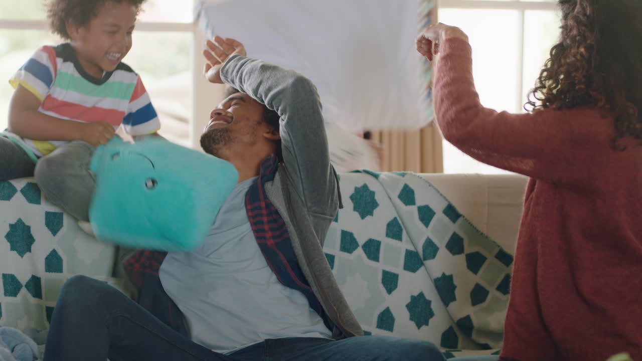 happy family having pillow fight mother and father enjoying playing with children at home having fun together on weekend