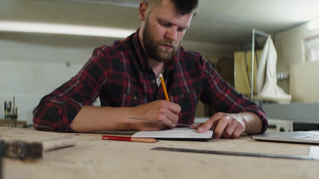 carpintero trabajando en planos en el taller